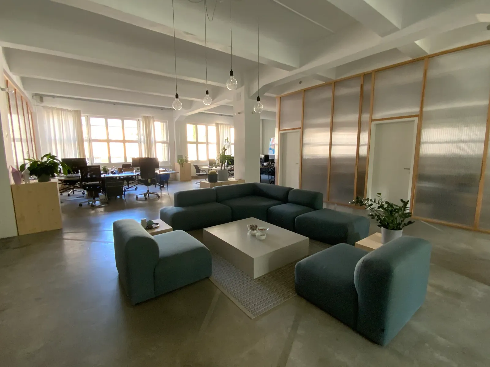 Zona de asientos de una oficina diáfana, vacía, con sofás y mesa baja.